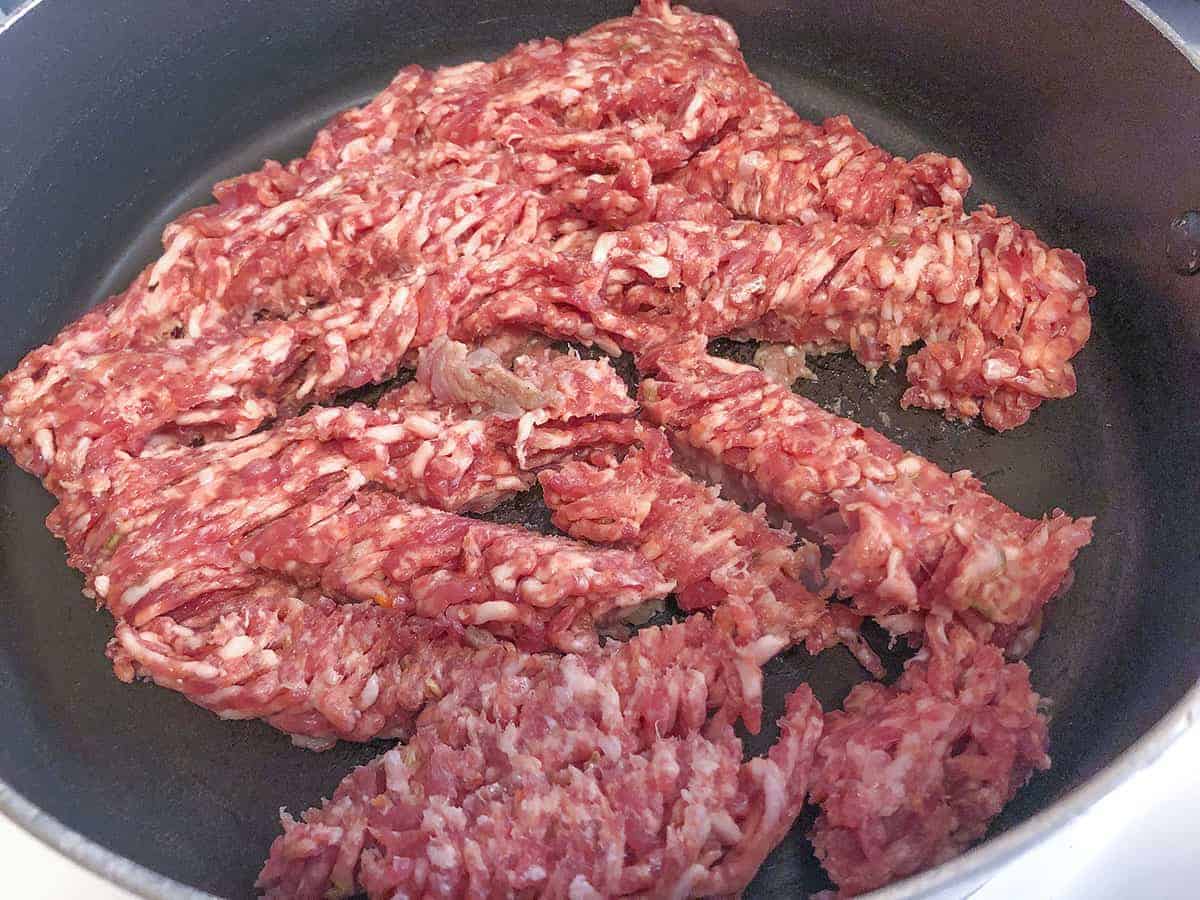 Raw sausage in a skillet, ready to brown.
