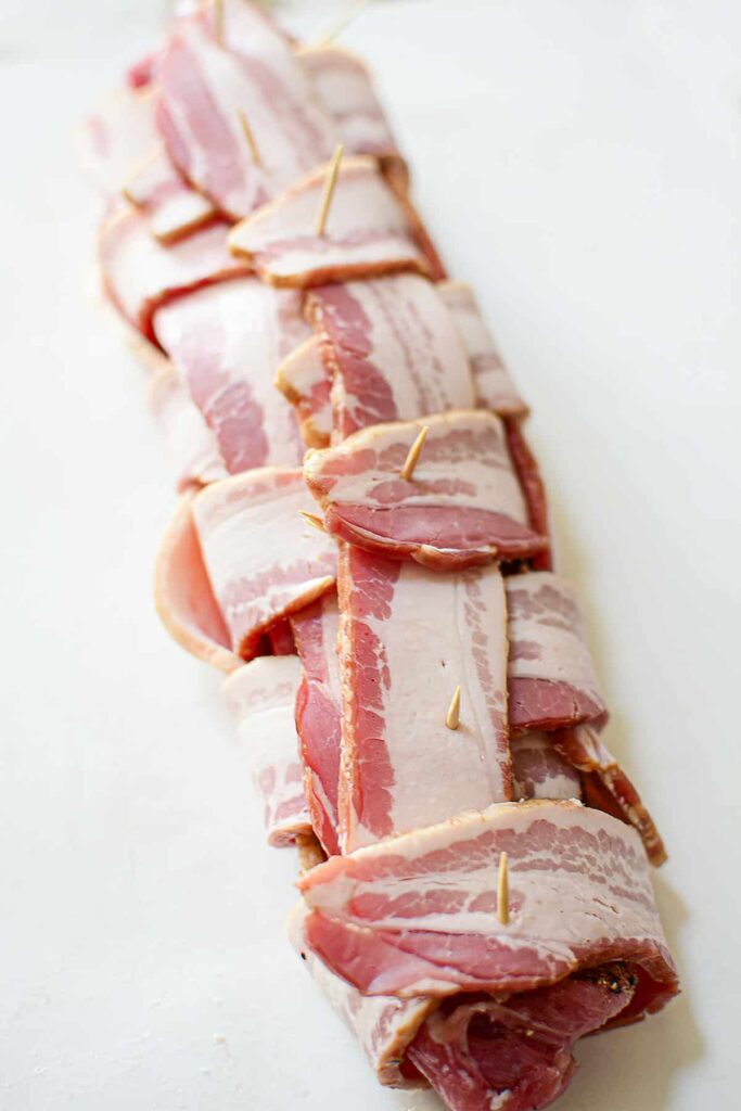 The bacon wrapped pork tenderloin secured with toothpicks