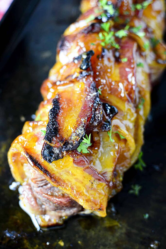 A closeup photo of the bacon wrapped tenderloin with apricot glaze on top.