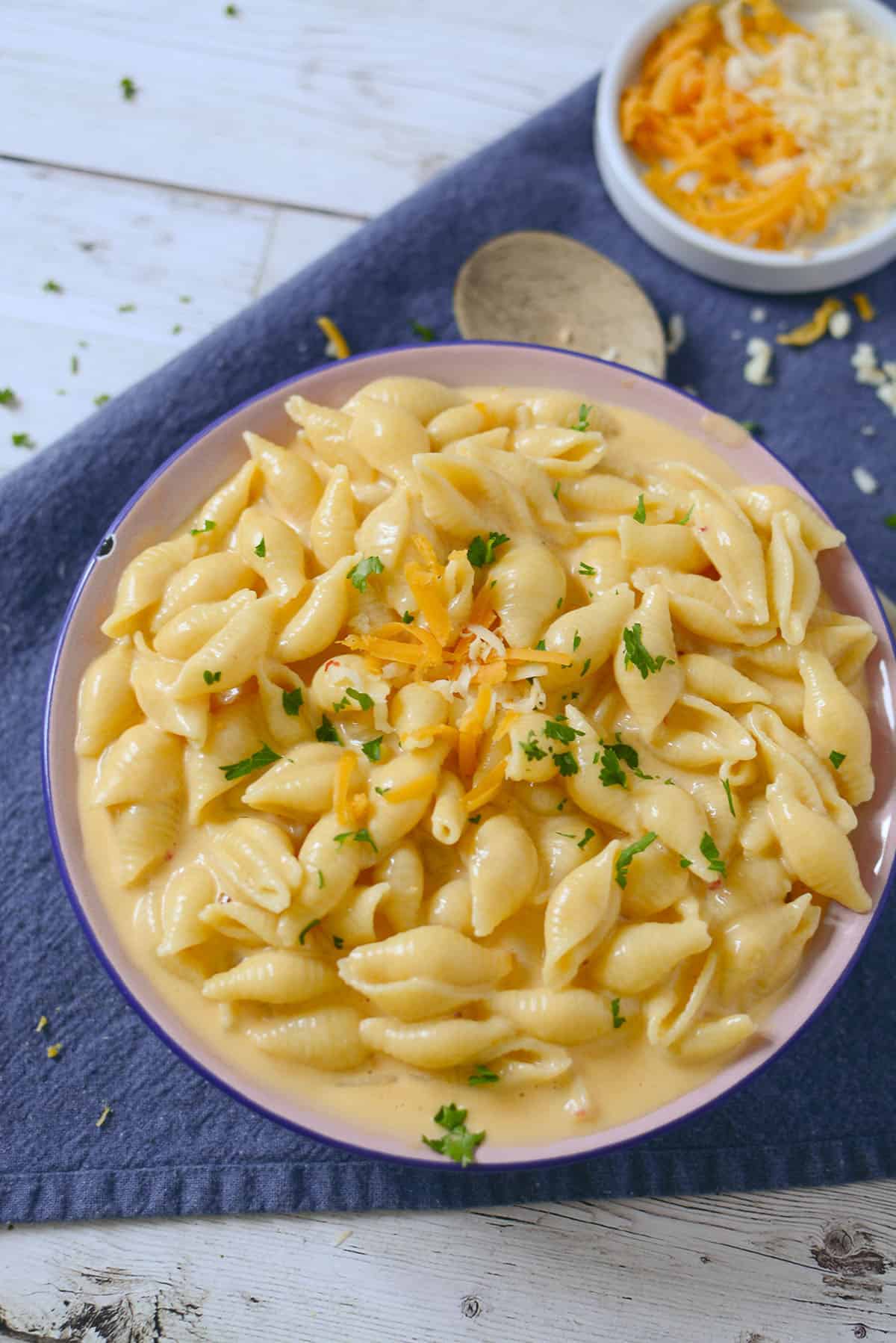 Mac and cheese in a bowl sitting on a blue napkin.