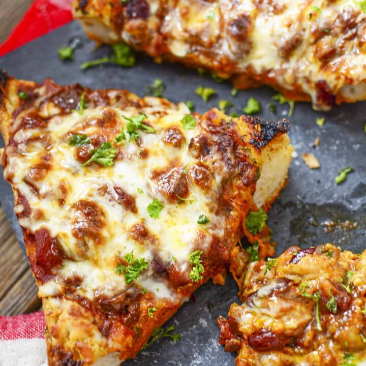 Three pieces of chili cheese toast on a slate serving board.