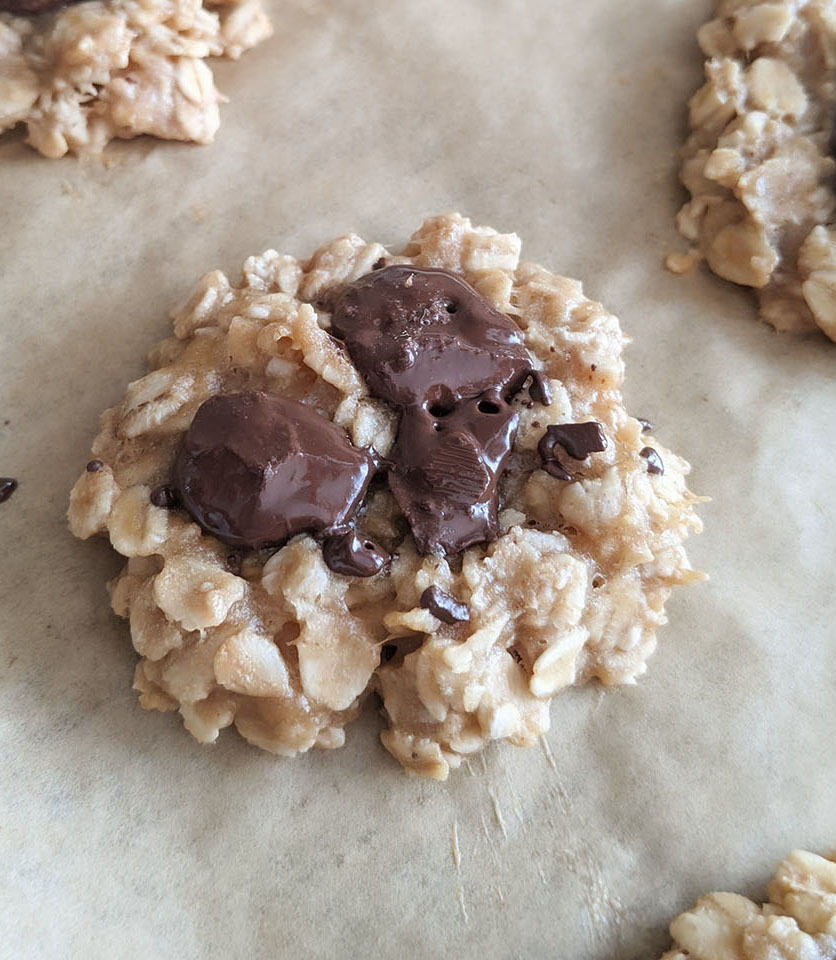 A banana cookie with melted chocolate chunks in the center of the cookie.