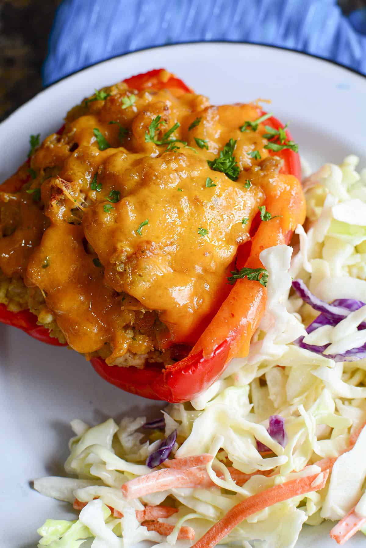Half of a chicken stuffed red pepper with creamy coleslaw beside it.