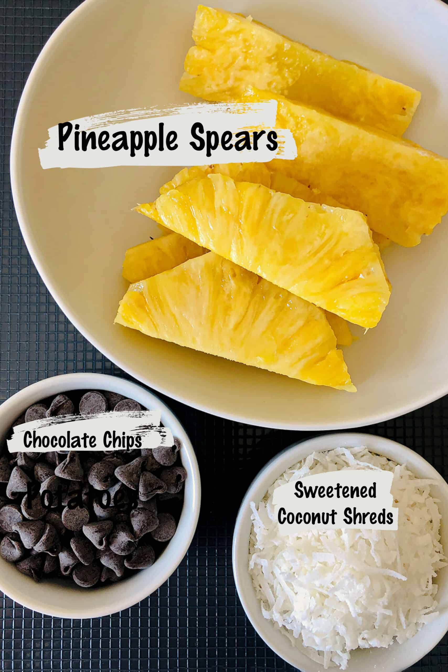 Labelled ingredients in bowls to make chocolate dipped pineapple spears.
