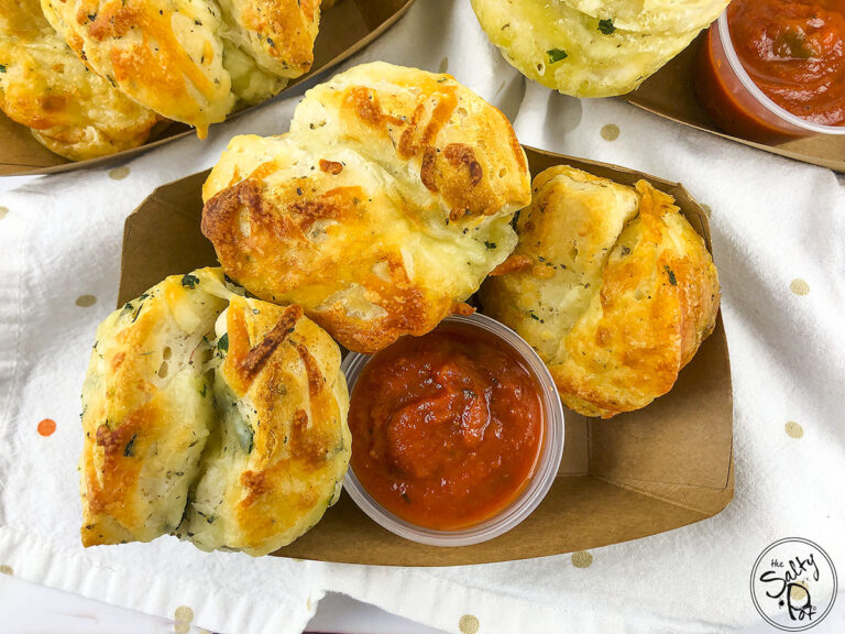 Garlic Knots in a container with Marinara dipping sauce.