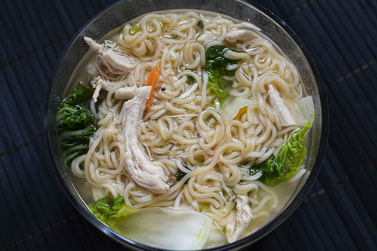An overhead view of the noodle soup on a black bamboo background.