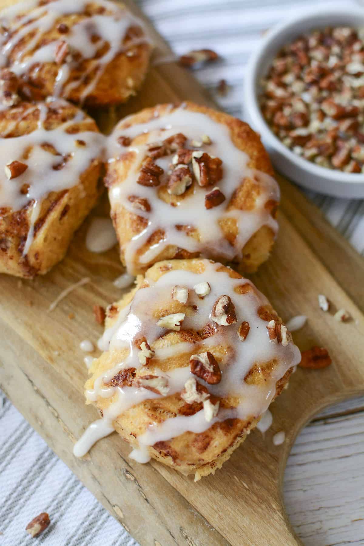 A top down view of the cinnamon buns on a wooden cutting board.