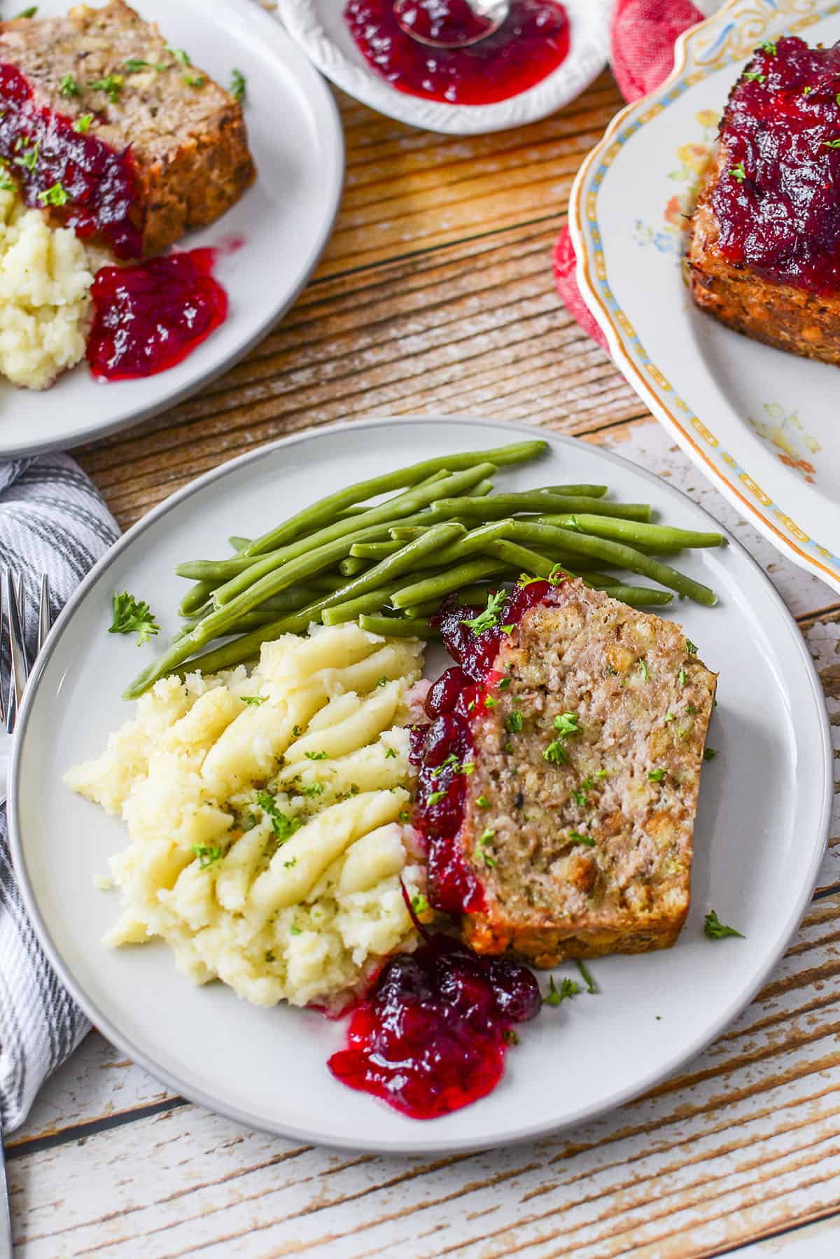 A plated turkey meatloaf dinner with potatoes and green beans on a grey plate and a wooden background.
