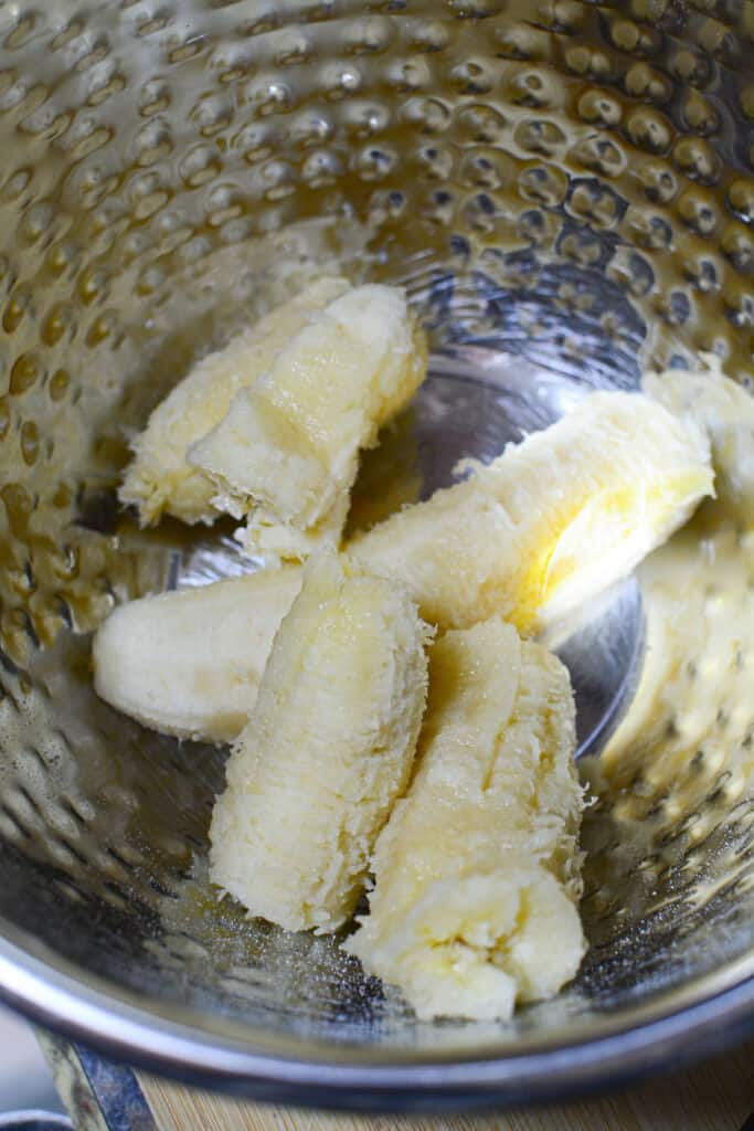 Two bananas in a silver bowl before being mashed.