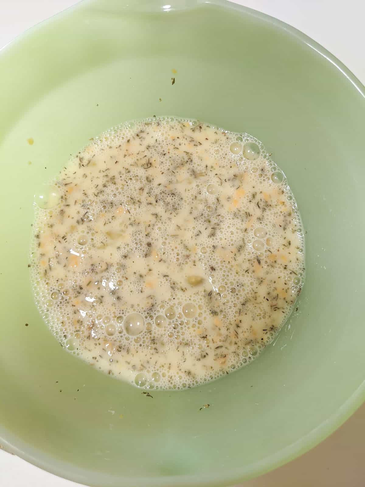 The egg mixture with the seasonings mixed in, in a green bowl. 