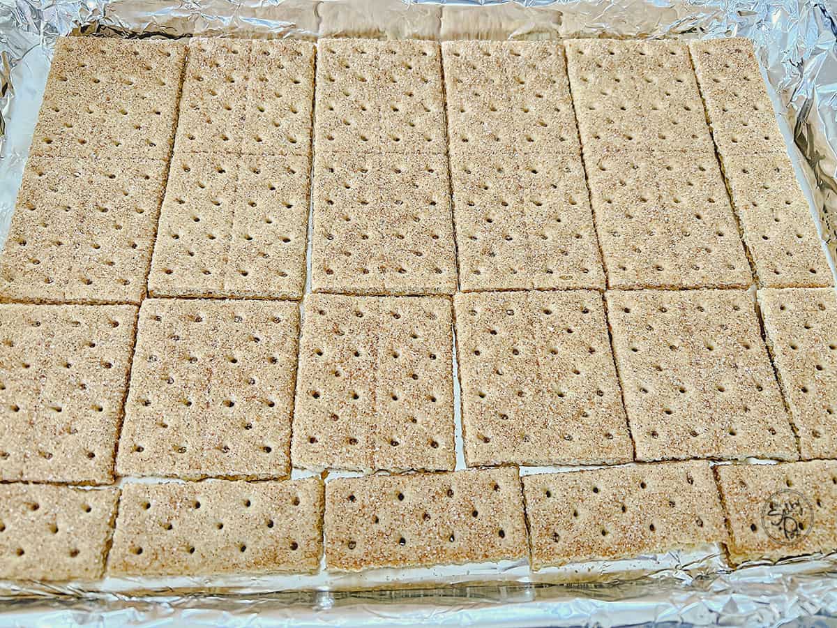 A baking sheet lined with foil, with graham crackers lined on top of the foil. 
