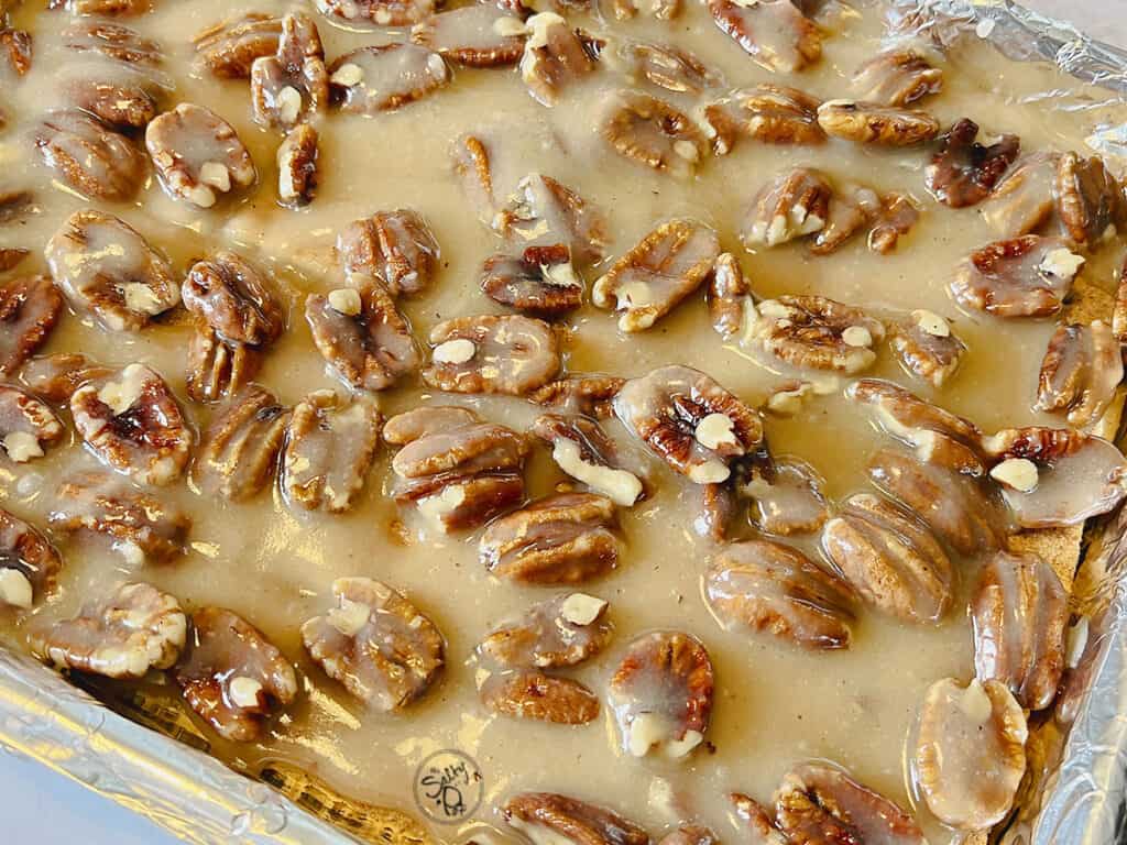 The butter/sugar/pecan mixture is poured over the graham crackers.