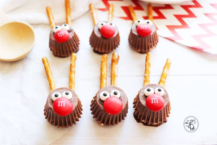 Six chocolate Rudolph Candy treats on a white table with red striped paper in the background.