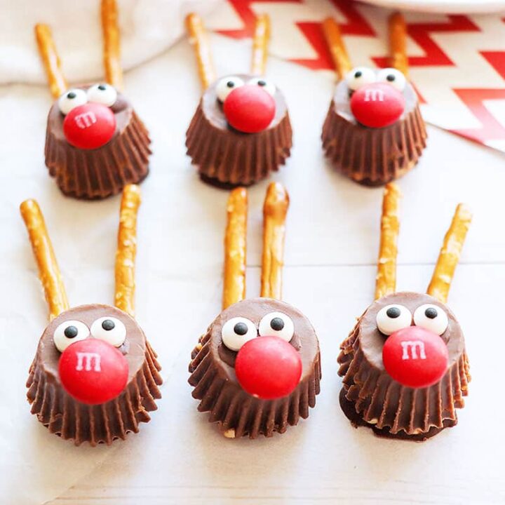 Six chocolate Rudolph Candy treats on a white table with red striped paper in the background.