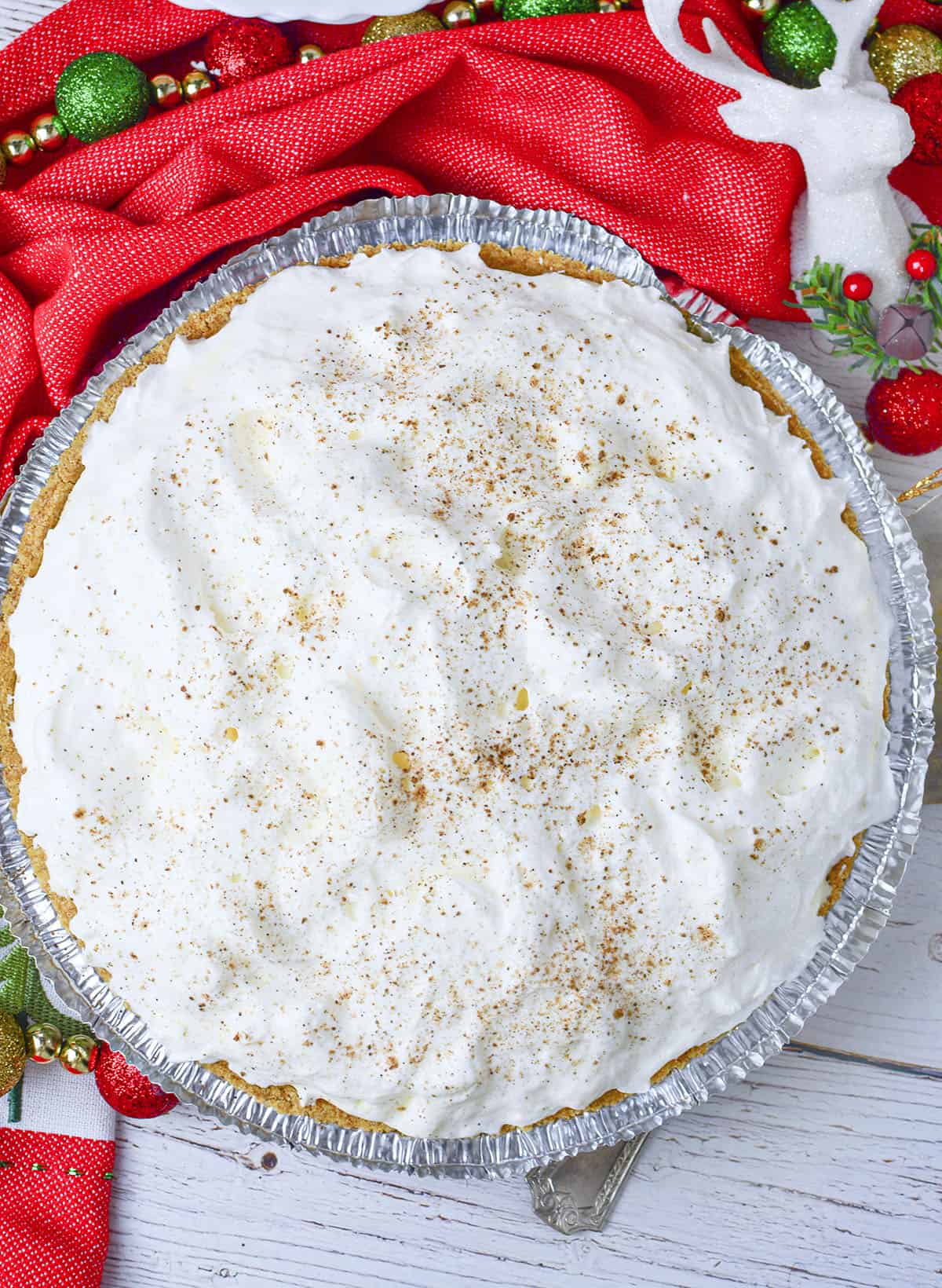 Eggnog pie on a wood background with festive red and green Christmas decor around the top