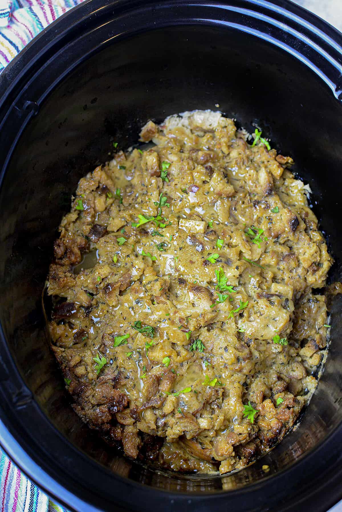The entire chicken dish in the slow cooker, photographed from above in a black slow cooker.