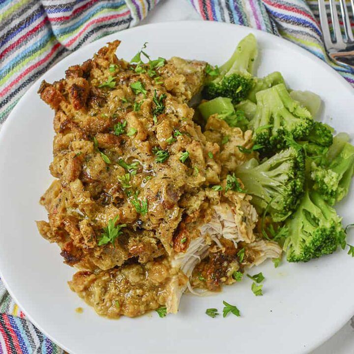 The chicken with stuffing casserole is on a white plate with green broccoli next to it.