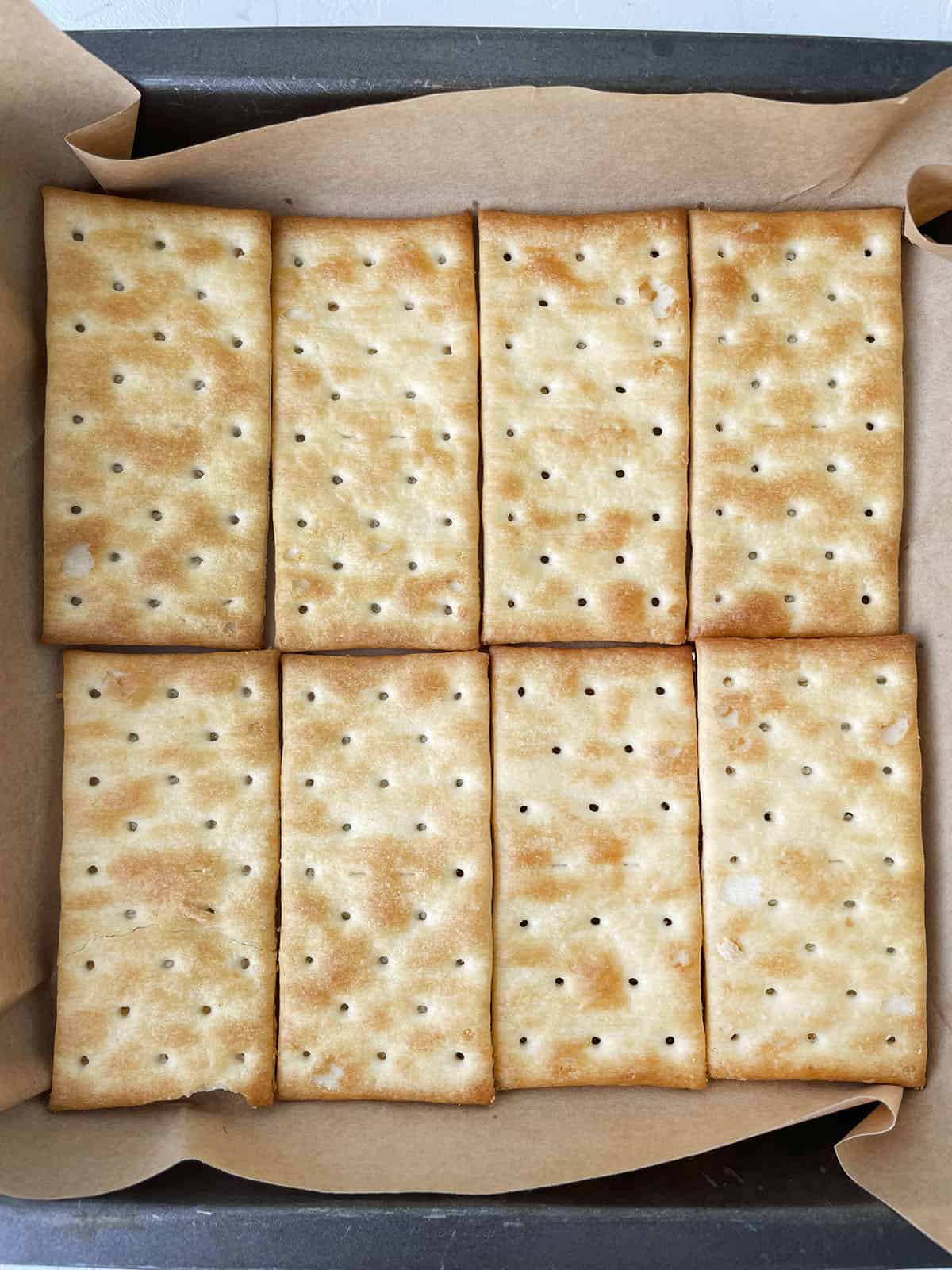 8 crackers in a baking pan with parchment paper.