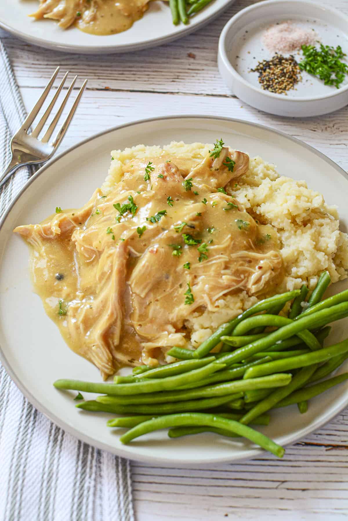 Chicken and gravy on a plate with green beans on the side.