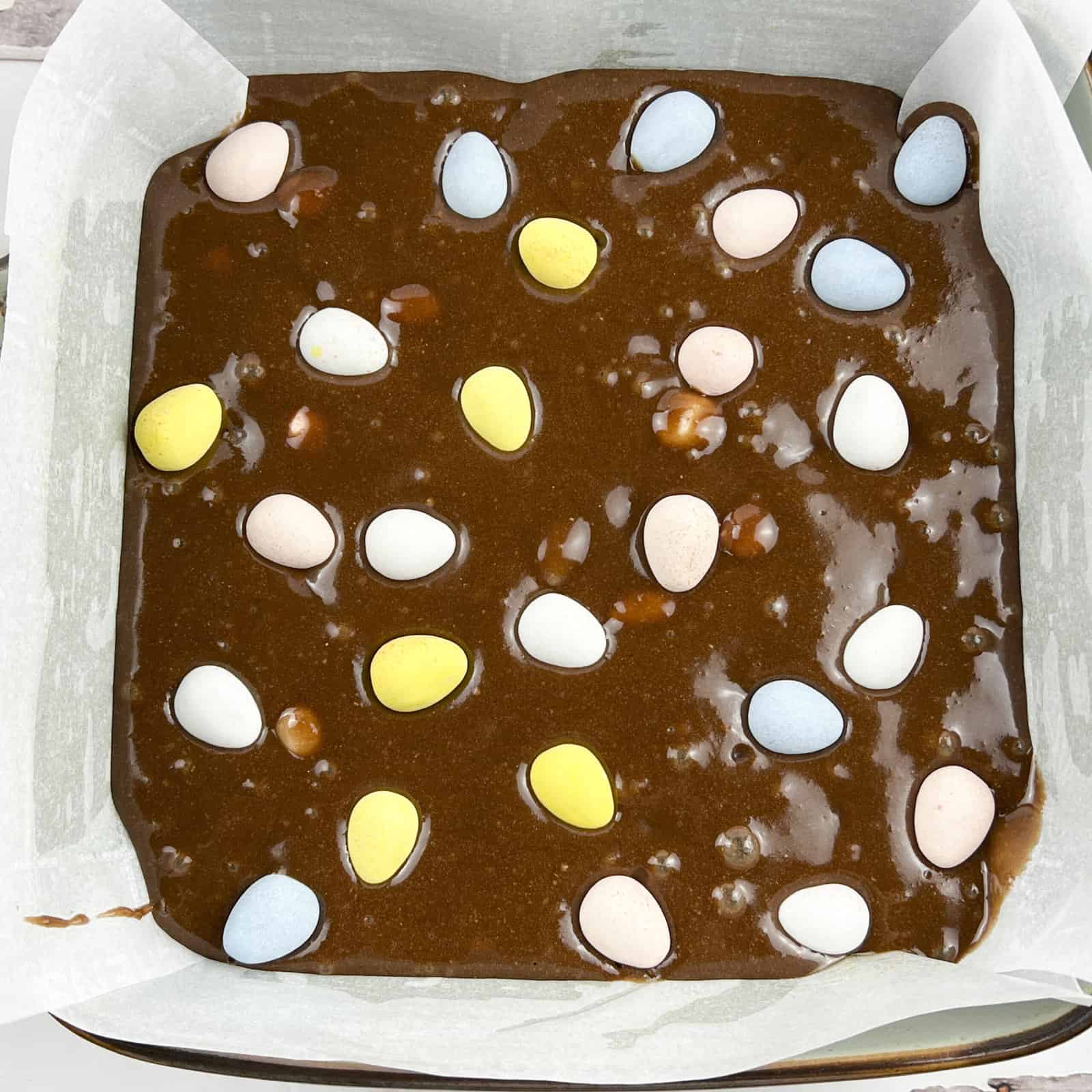 Brownie batter with chocolate mini eggs sprinkled on top.
