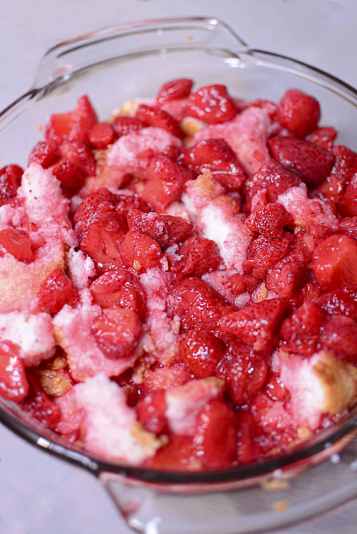 The jello strawberry mixture is poured over the angel food cake in the baking dish.