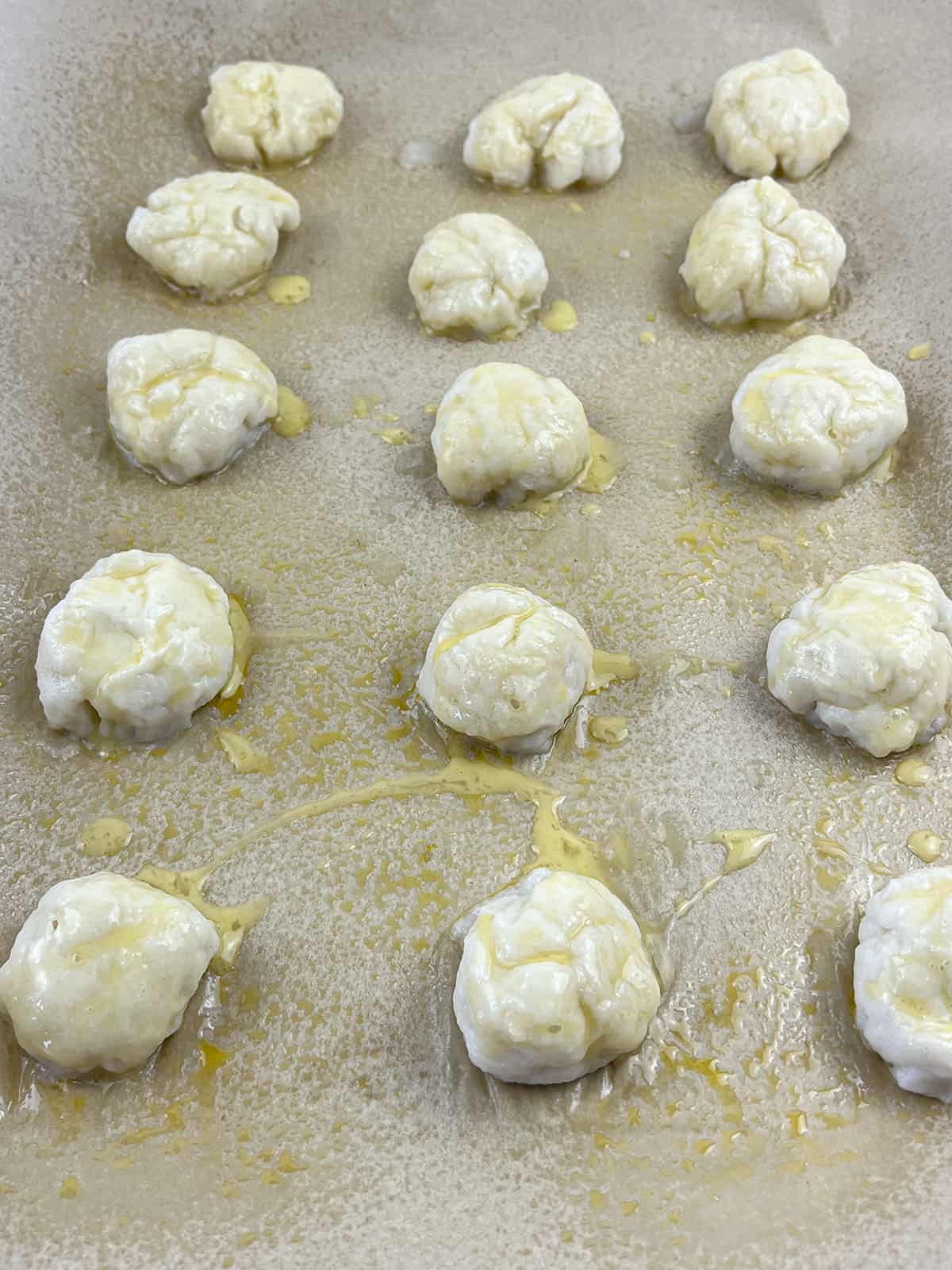 Boiled pretzel bites with egg wash, ready to go into the oven on a baking sheet.