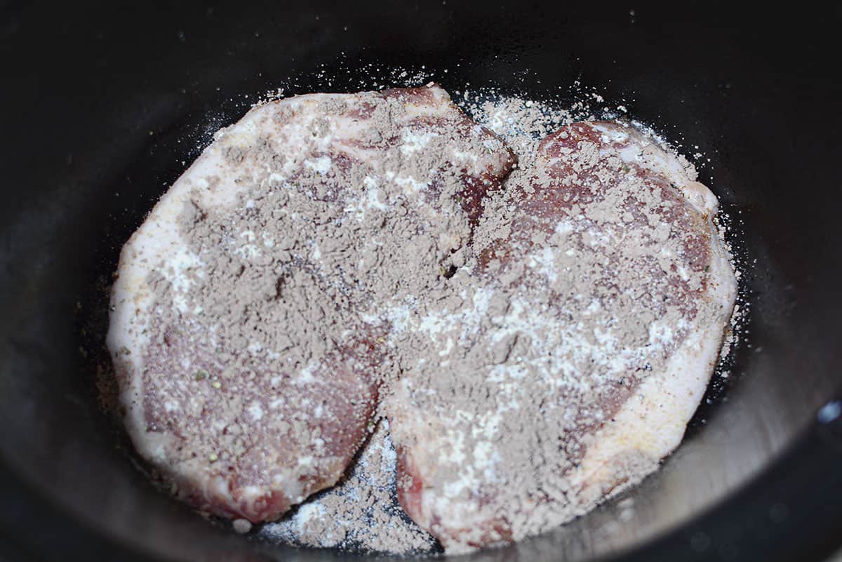Seasoning are sprinkled over the top of the chops in the crock pot.