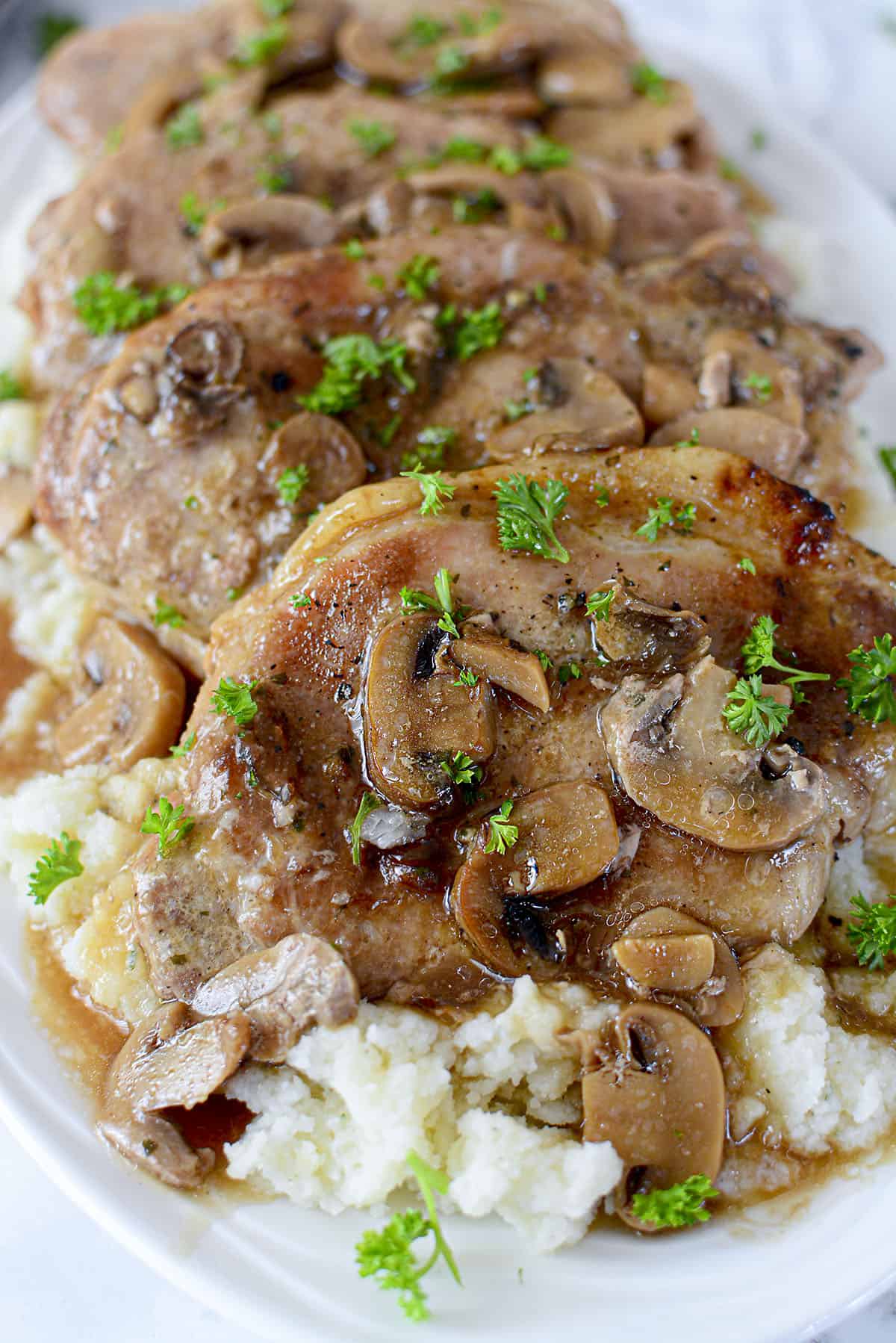 Slow cooker pork chops with gravy and mushrooms on mashed potatoes.