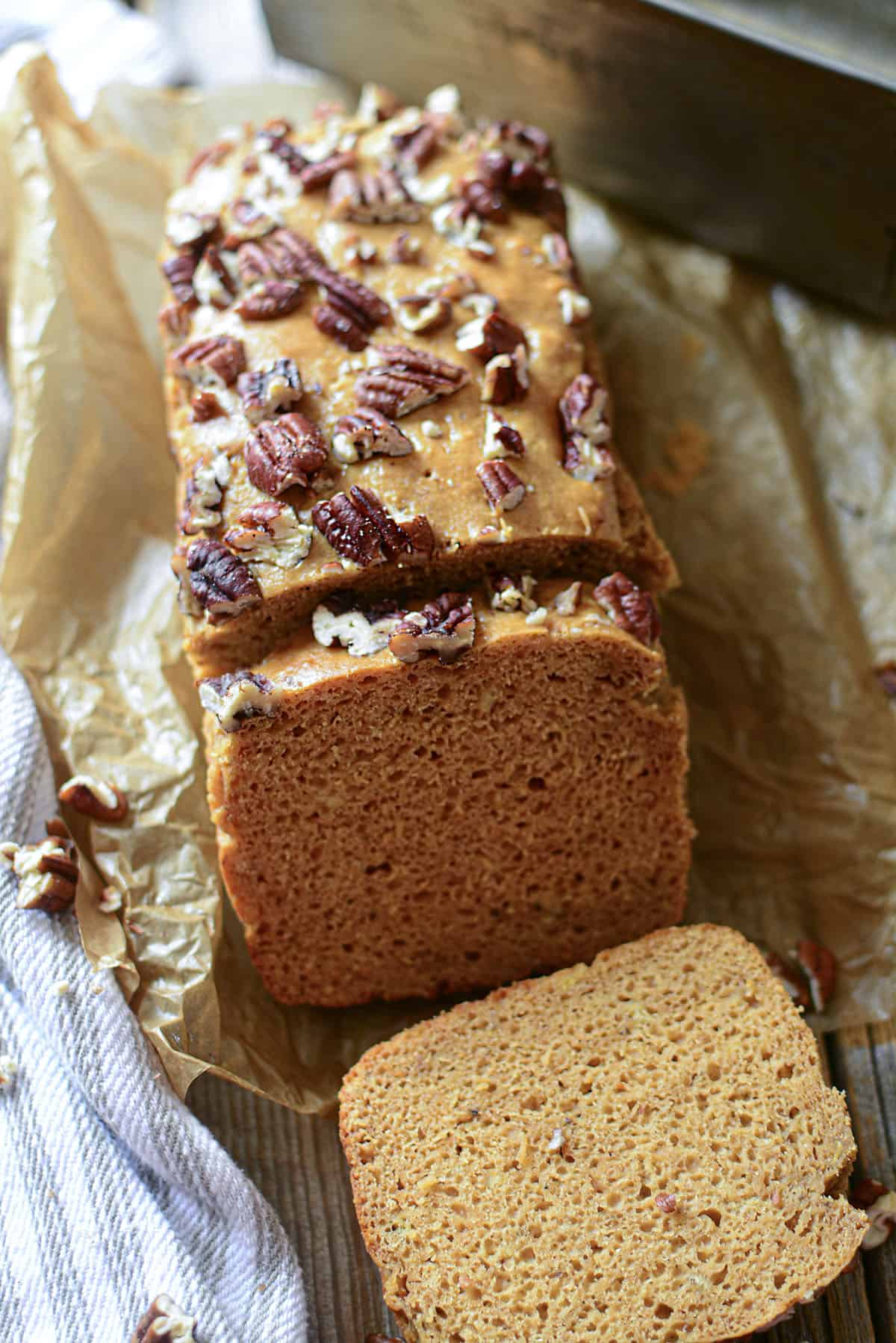 Banana bread with two slices resting on brown parchment paper.