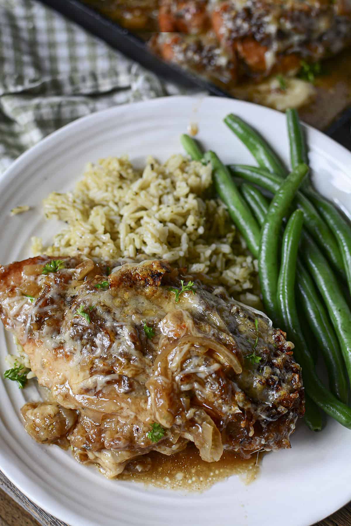One onion chicken breast plated with green beans and rice.