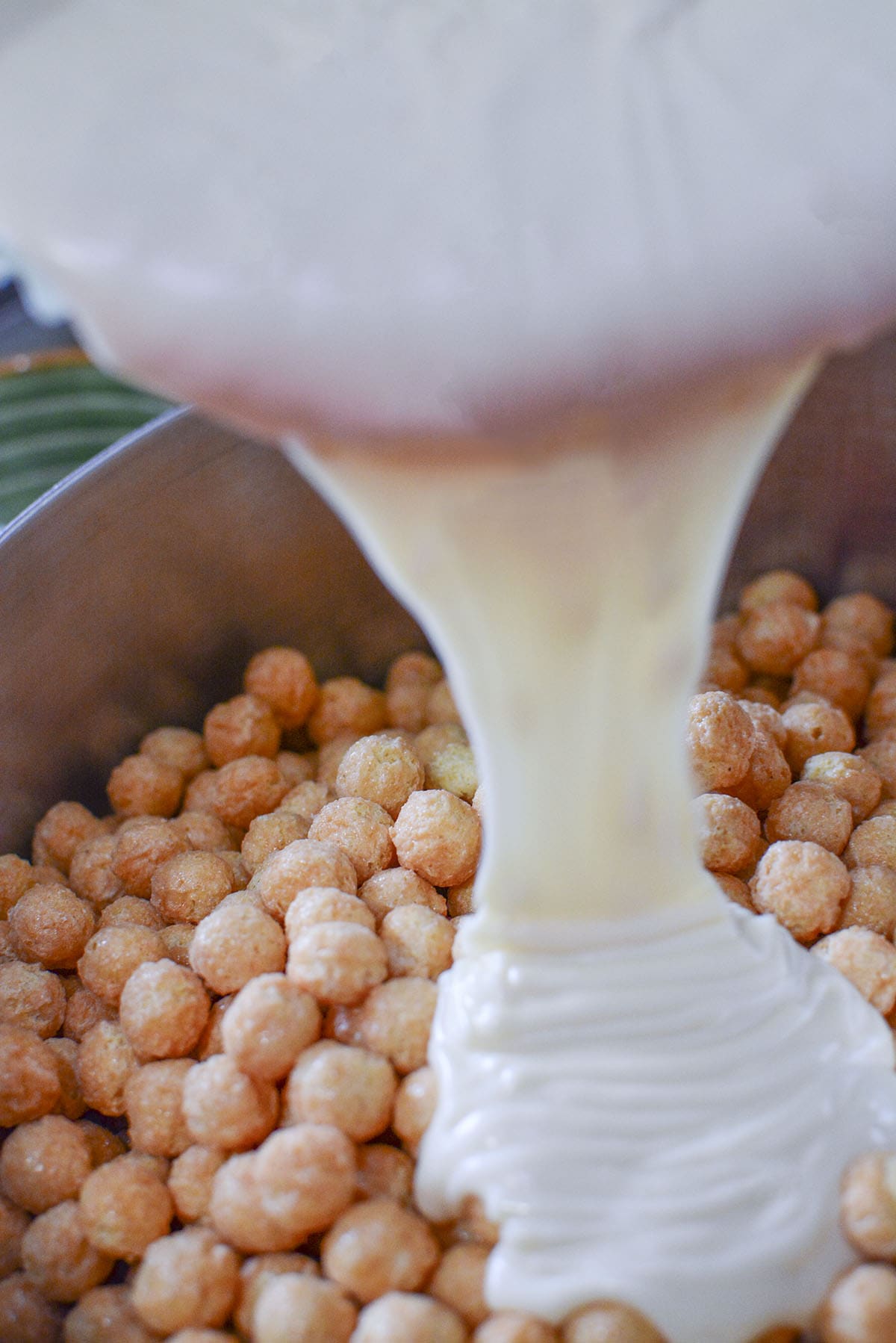 Pouring the melted white chocolate over the cereal.