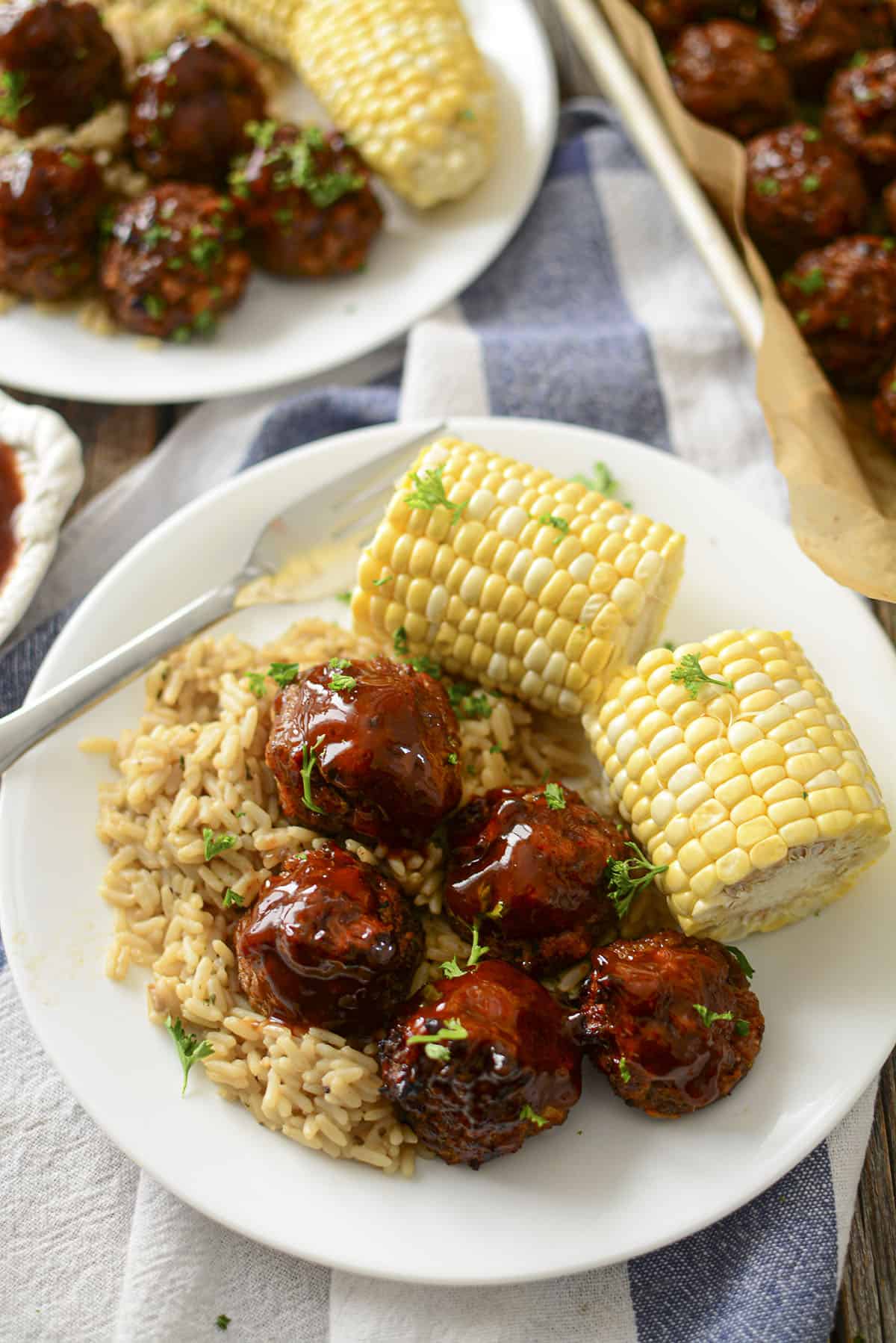 5 Meatballs on rice with corn on the cob.