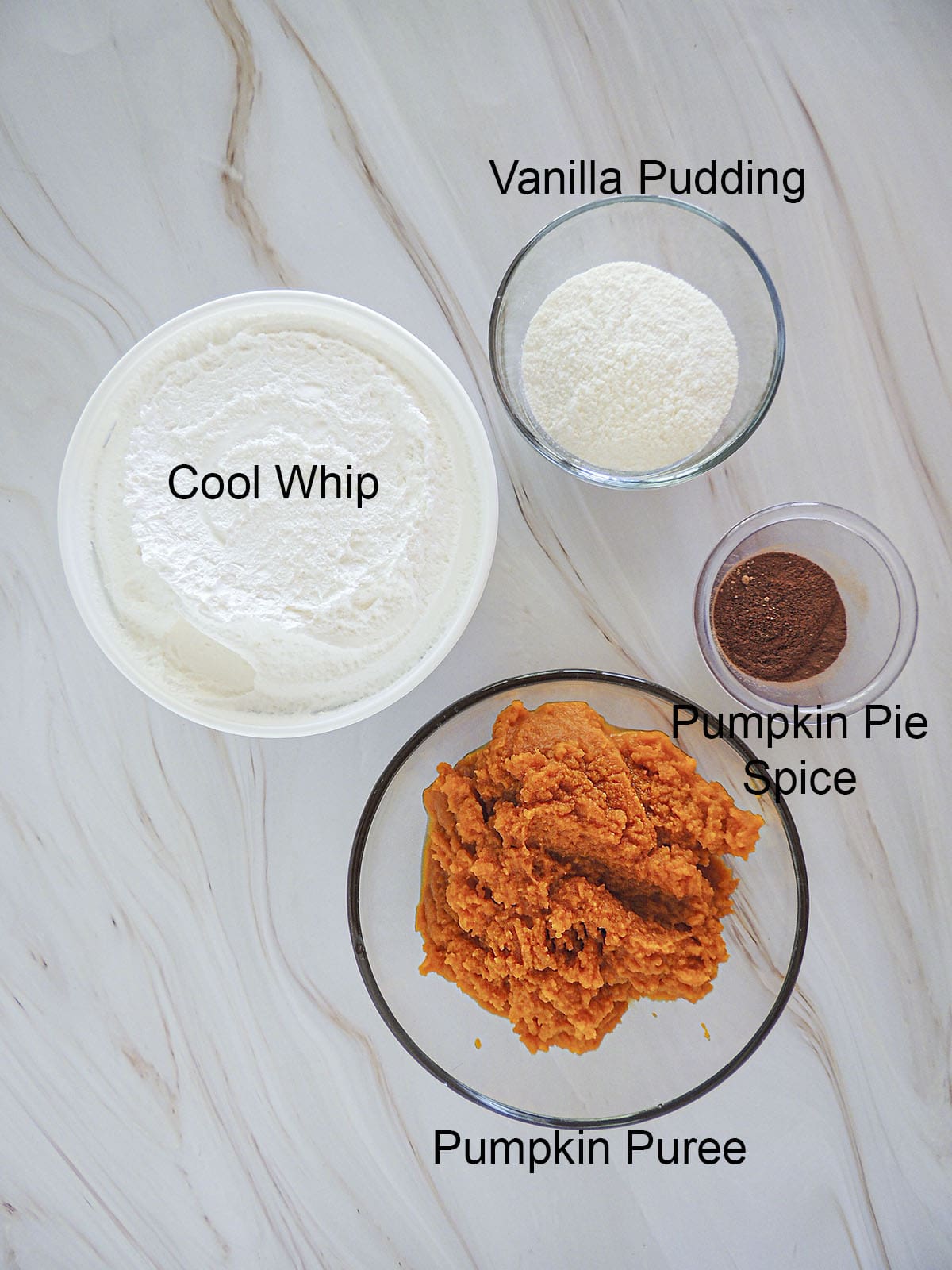 Ingredients for the pumpkin fluff. Cool whip, vanilla pudding powder, pumpkin pie spice and pumpkin puree.