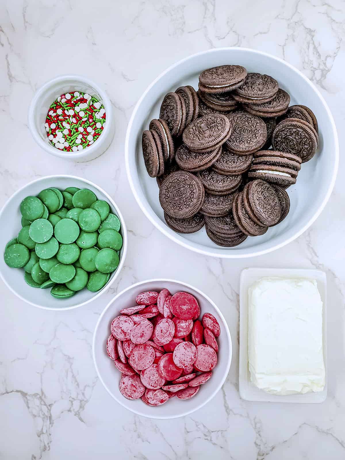 Ingredients for the cookie balls. Oreos, cream cheese, chocolate candy melts (red and green) and Christmas sprinkles.