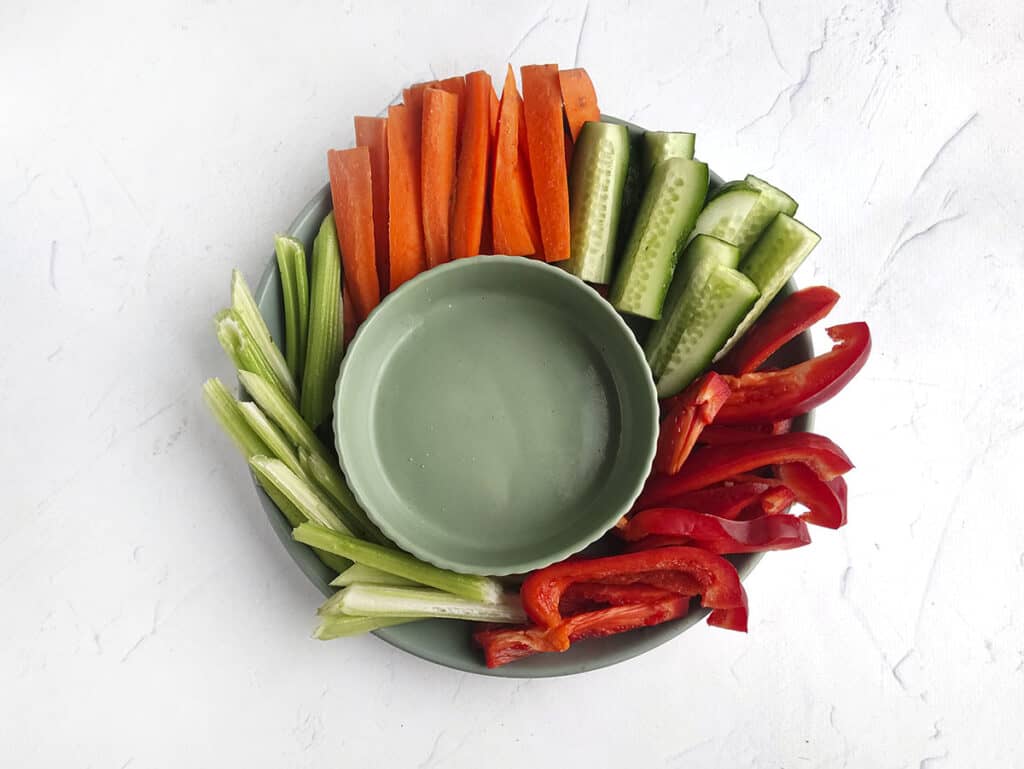 An empty bowl surrounded with cut vegetables, ready to be filled with the ranch dip.