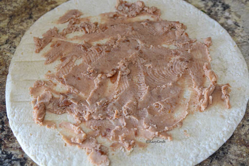 Refried beans spread over a tortilla.
