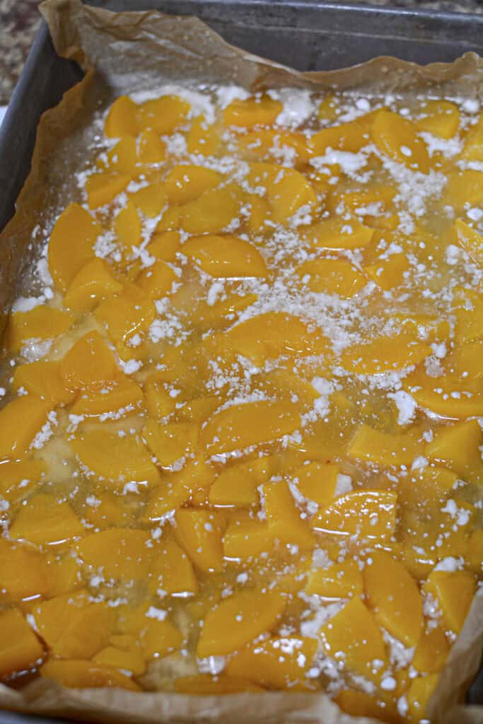 The peaches, undrained, poured on top of the cake mix in the pan.
