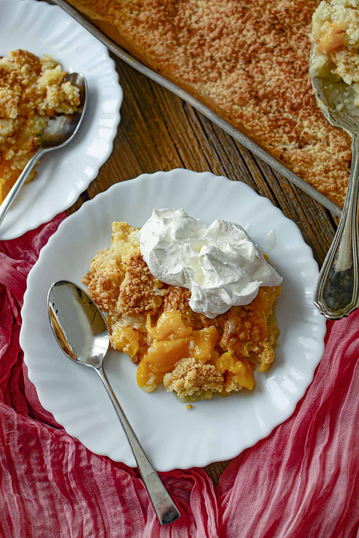 A single serving of 3 ingredient peach cobbler on a white place.