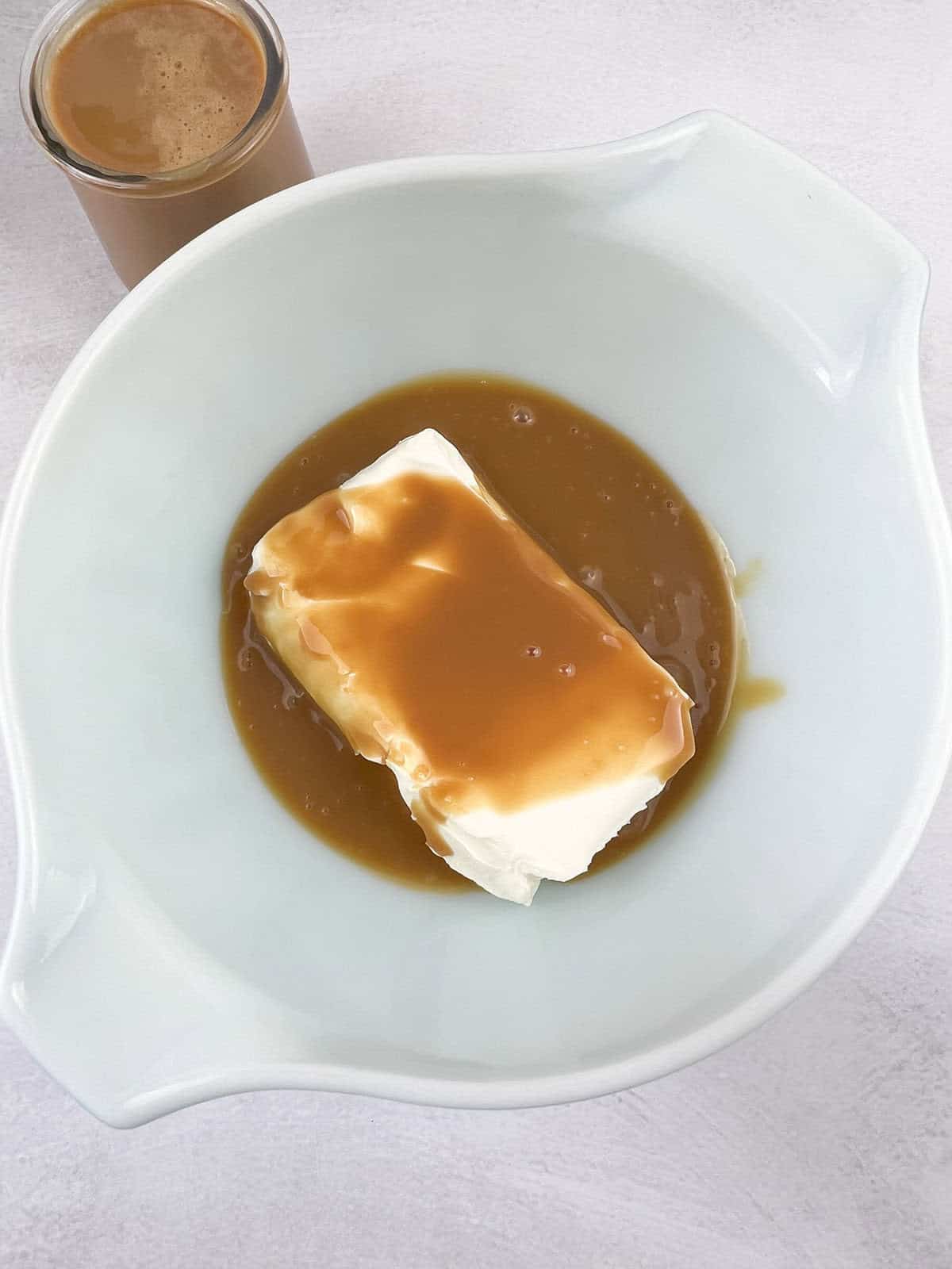 Adding the caramel sauce in the bowl with the cream cheese. 