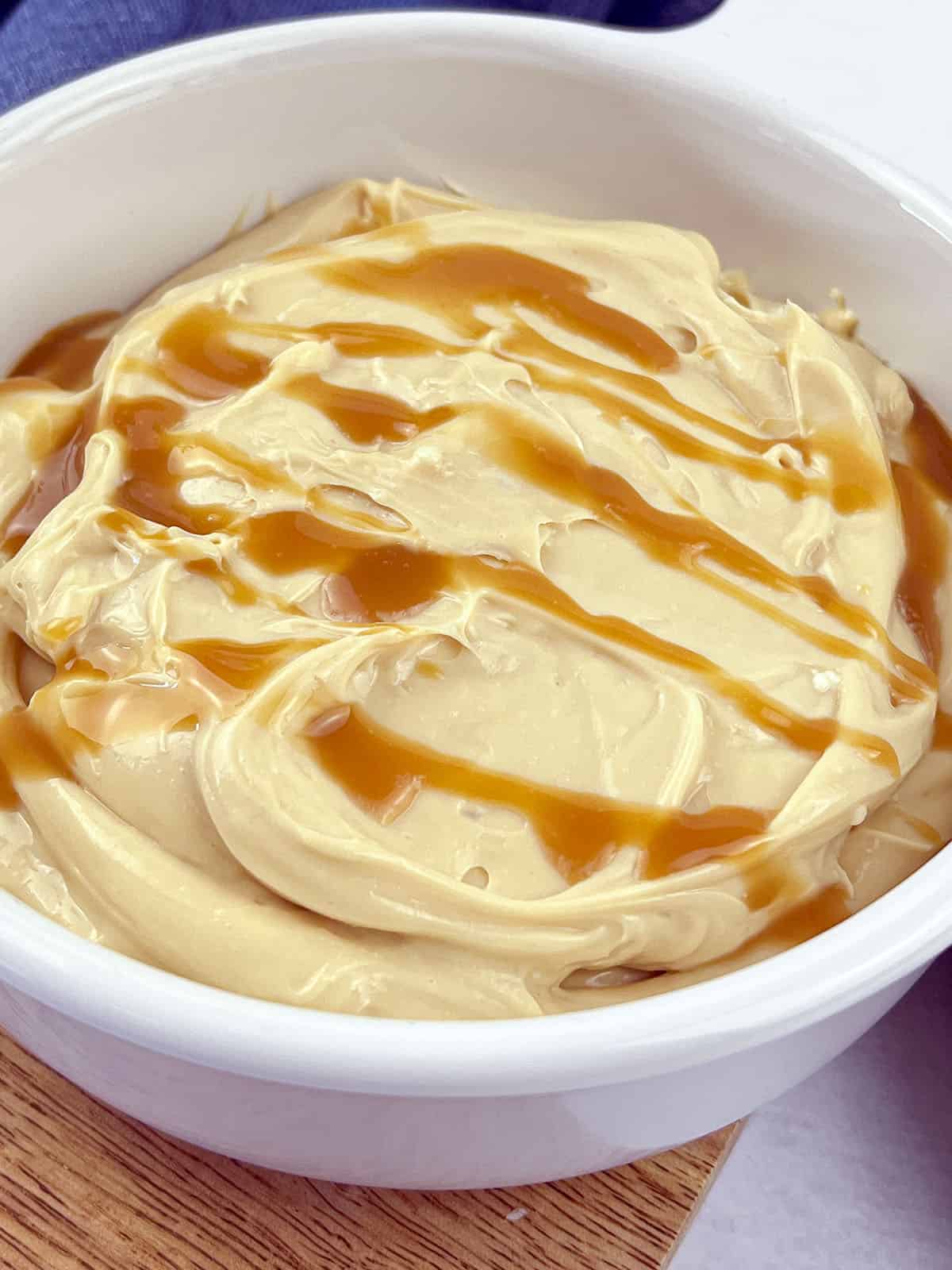 A close up image of the caramel dip in a white serving bowl.