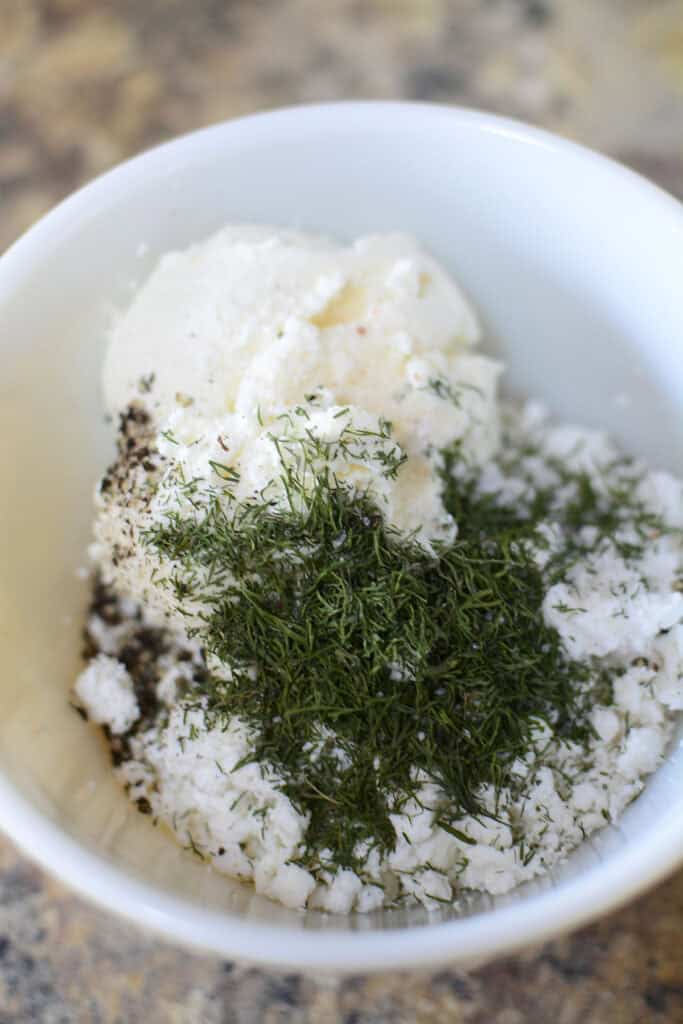 Dill, salt, pepper, ricotta and cottage cheese in a bowl.
