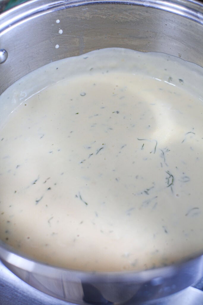 Alfredo sauce in a pot with dill.