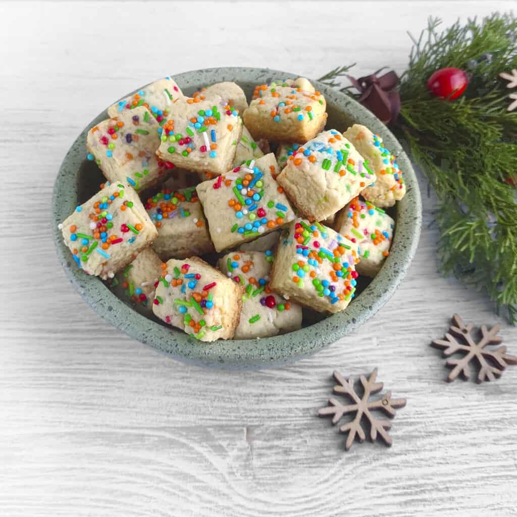 Cookie bites in a bowl with little wooden snowflakes. Square image.