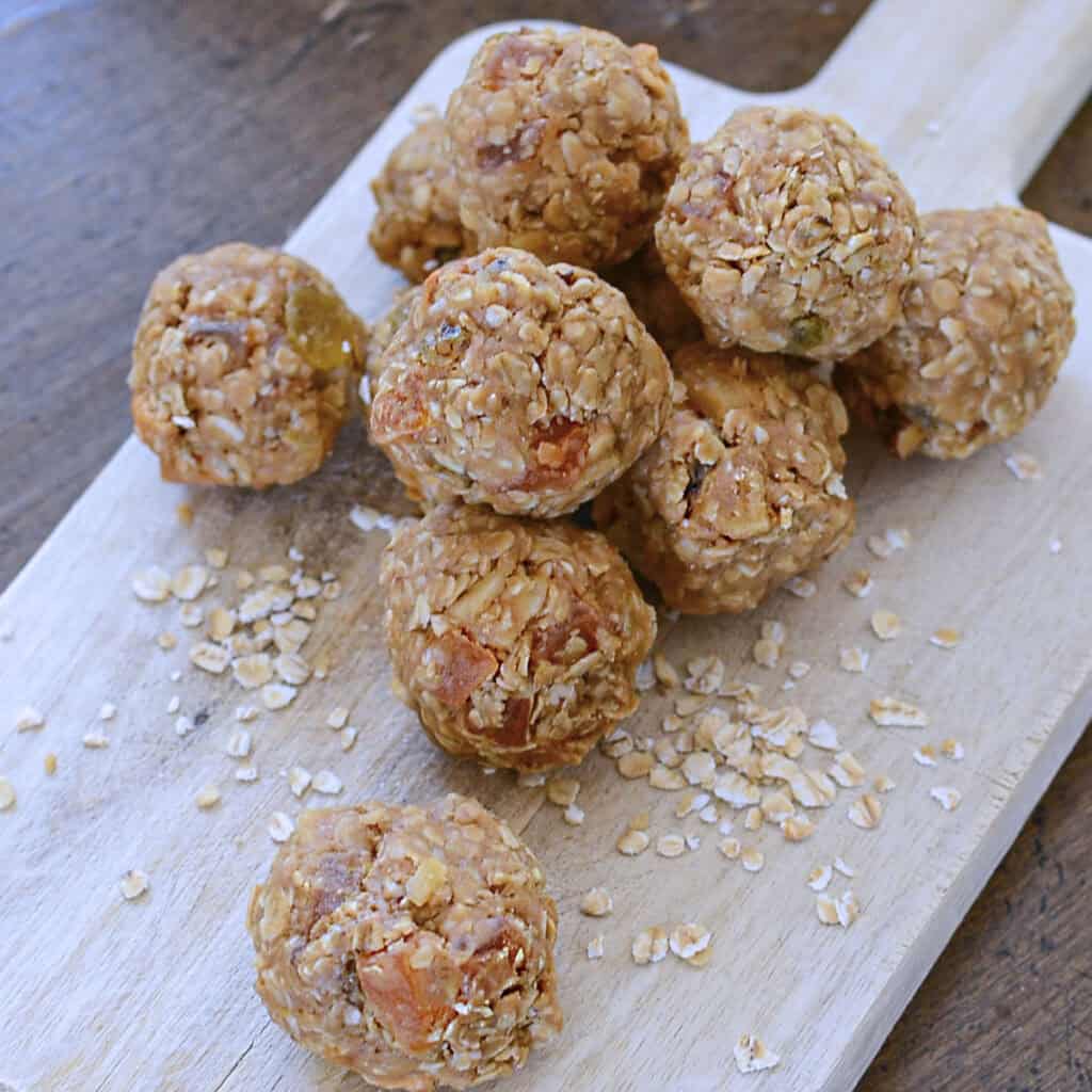 Tropical bliss balls on a wooden cutting board, square image.