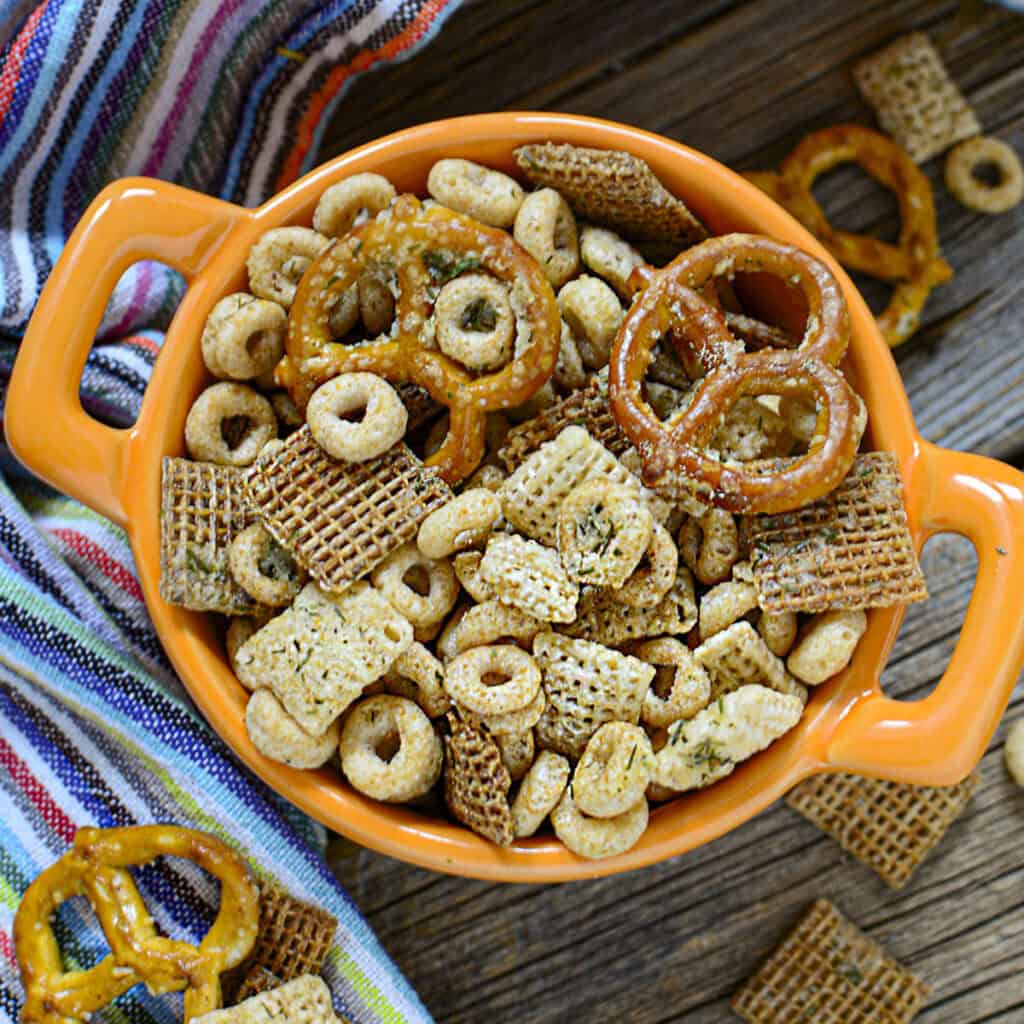 Game day snack mix in an orange dish, square image.