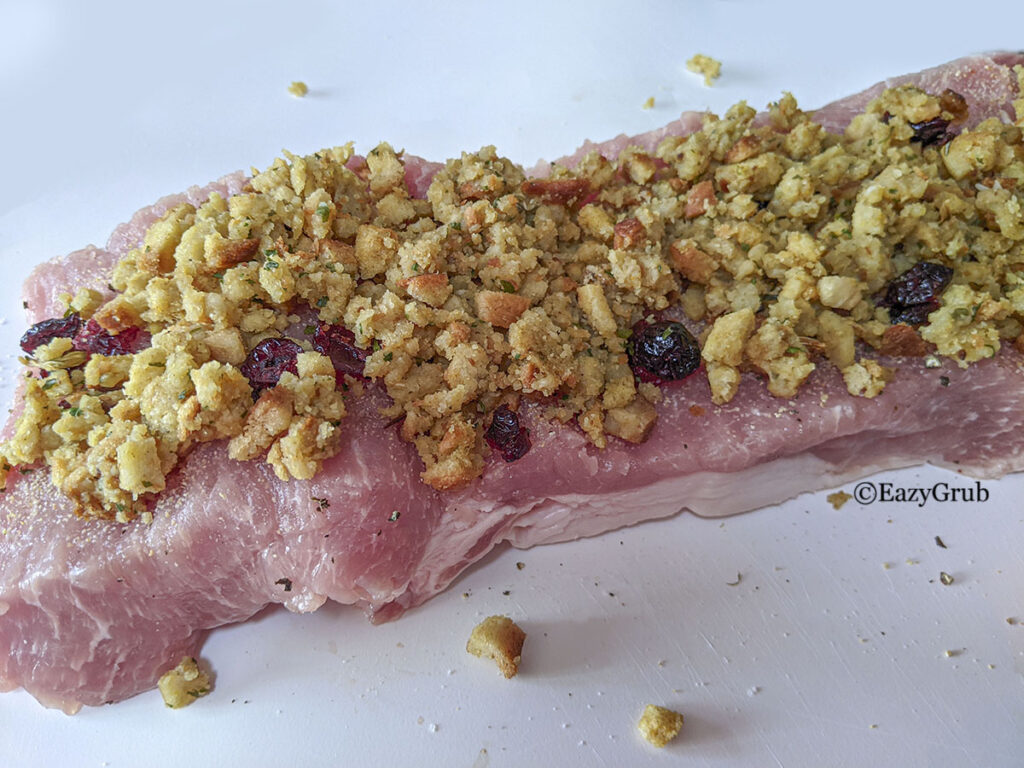 A pork loin roast with stuffing spread on top of it. 