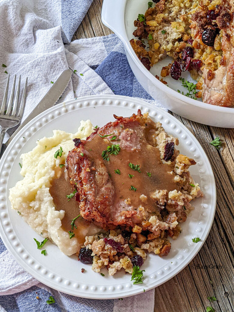 Cranberry stuffed pork loin roast on a white plate with mashed potatoes.