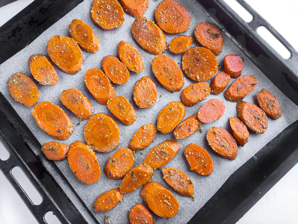 Carrot medallions arranged on a baking sheet to go in the oven.