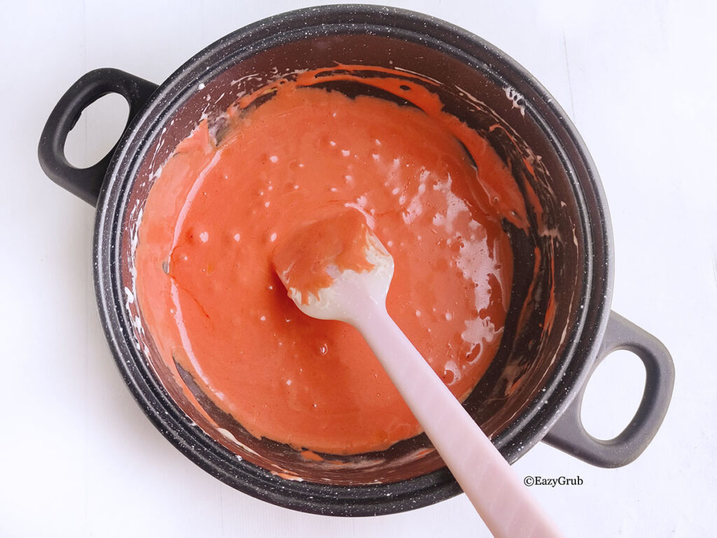Marshmallows and food coloring added to a pot. There is a spoon sticking out of the pot on the bottom right.