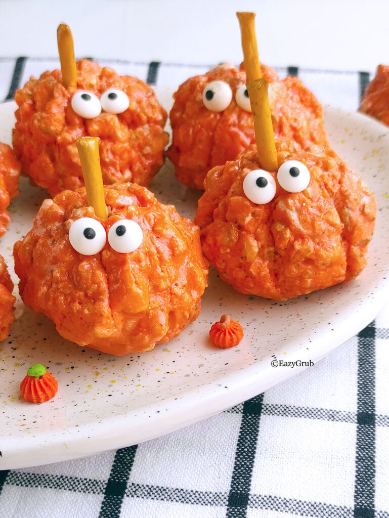 4 pumpkin puff cereal treas on a plate with googly candy eyes.